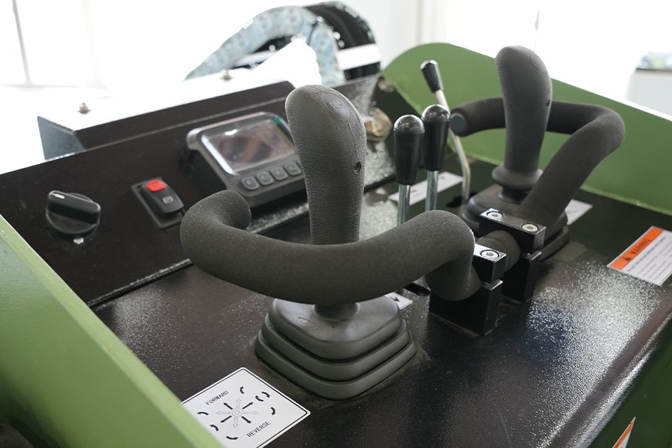 Close-up of skid loader controls with joysticks and foot pedals.