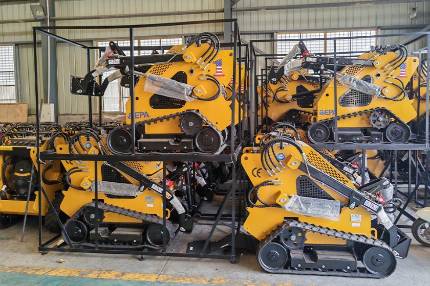 Bobcat, Caterpillar, and John Deere skid loaders parked on a construction site